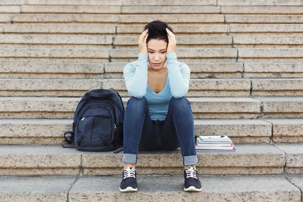 Açık havada merdivenlerde oturan çaresiz öğrenci