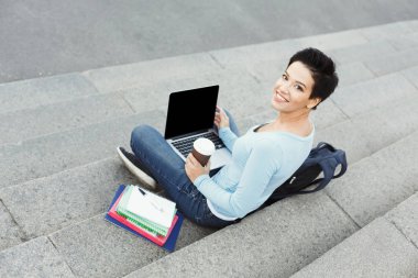 Gülümseyen genç kadın dizüstü açık havada kullanma