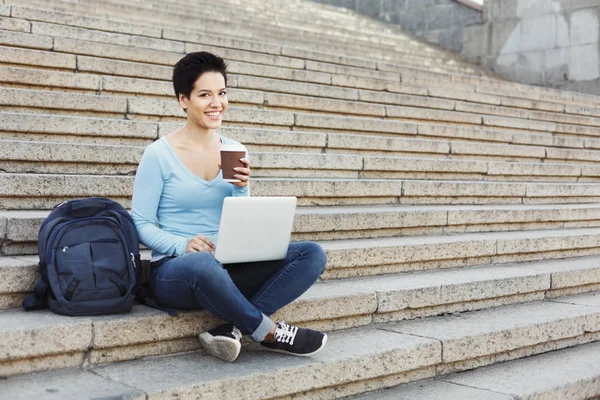 Smilende student som sitter i trapper med laptop – stockfoto