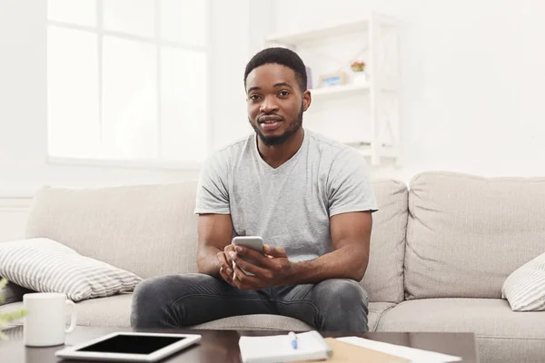 Sorrindo jovem em casa mensagens no celular — Fotografia de Stock