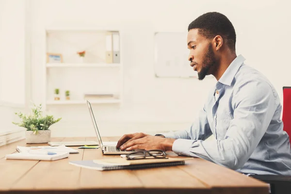 Ung svart affärsman arbetar med laptop — Stockfoto