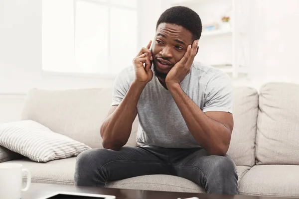 Сумний молодий чоловік розмовляє по мобільному телефону вдома — стокове фото