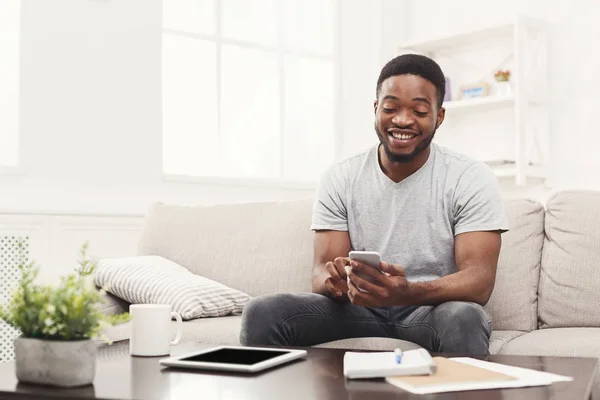 Jovem feliz em casa mensagens no celular — Fotografia de Stock