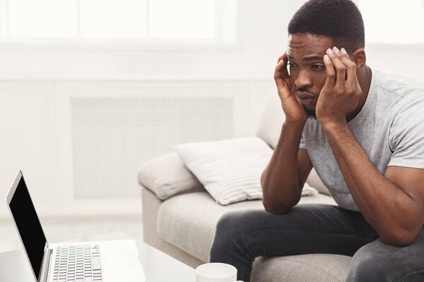 Young african-american man having headache at home