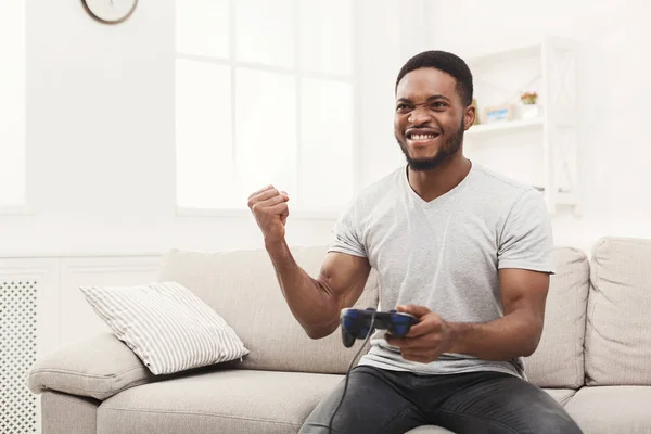 Feliz joven afroamericano en casa jugando videojuegos y gana —  Fotos de Stock