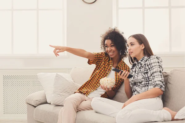 Mujeres jóvenes sonrientes viendo la televisión en casa —  Fotos de Stock