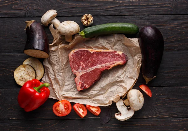 Raw t-bone steak on craft papper on dark background — Stock Photo, Image