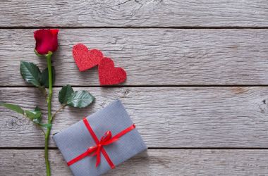 Sevgiliye arka plan kırmızı gül çiçek, kağıt kalp, rustik ahşap hediye kutusu ile