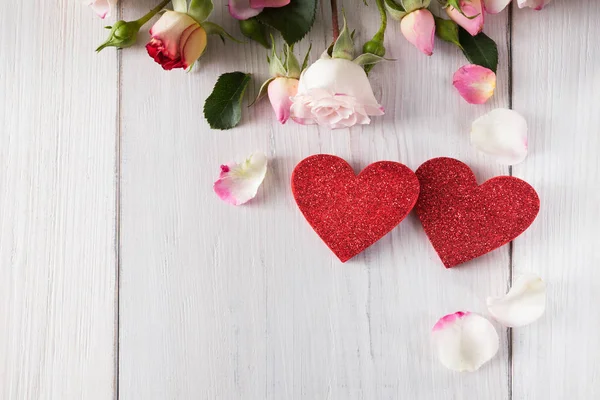 Rosa rosa flores pétalos y hechos a mano de madera brillo corazones en madera rústica blanca — Foto de Stock