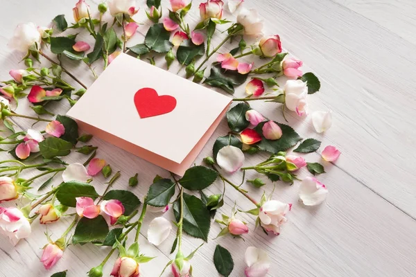 Carte papier à la main en rose cadre de roses naturelles sur bois rustique blanc — Photo