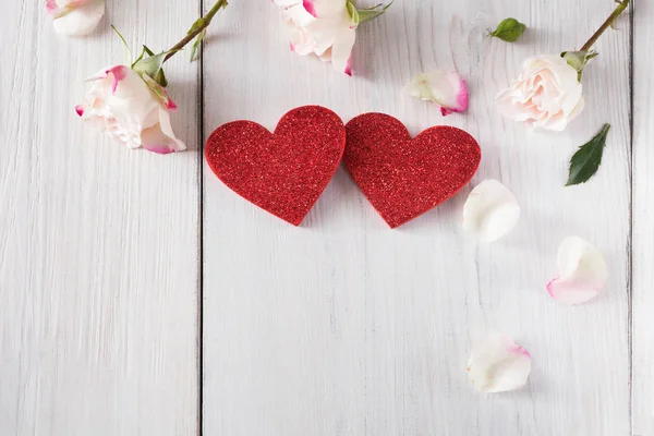 Πέταλα ροζ τριαντάφυλλο λουλούδια και χειροποίητα ξύλινα glitter καρδιές σε λευκό ρουστίκ ξύλο — Φωτογραφία Αρχείου