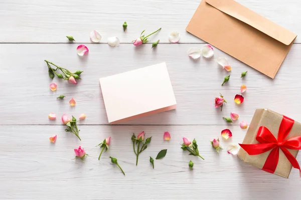 Валентинний фон з порожньою паперовою вітальною листівкою та подарунковою коробкою в рожевій рамці з квітами троянд — стокове фото