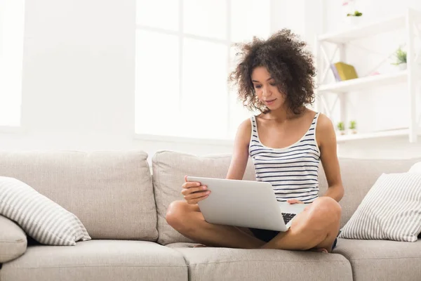 Junges Mädchen mit Laptop sitzt auf beigem Sofa — Stockfoto