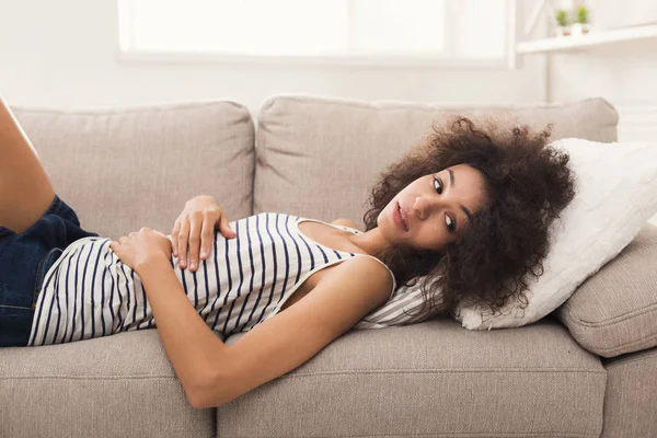 Triste femme afro-américaine sur le canapé à la maison — Photo