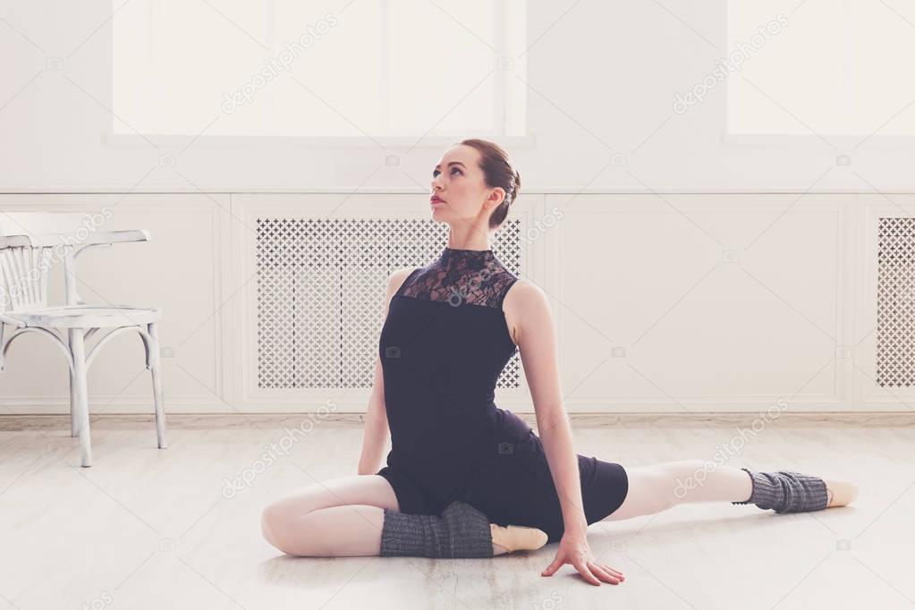 Classical ballet dancer stretching in white training class