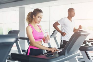 Erkek ve kadın, çift koşu bandı üzerinde spor salonunda