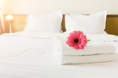 Havlu ve yatak otel odasında çiçek yığını