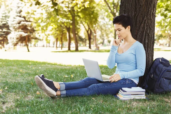 Donna seduta sull'erba con computer portatile all'aperto — Foto Stock