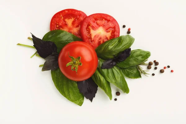 Tomates vermelhos e folhas de manjericão isoladas em branco — Fotografia de Stock