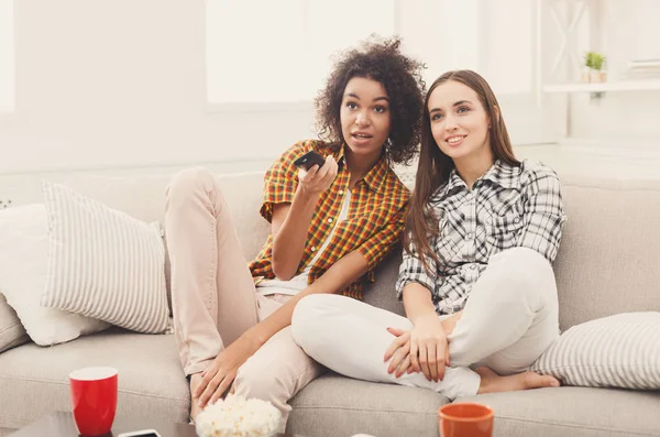 Lächelnde Freundinnen, die zu Hause fernsehen — Stockfoto