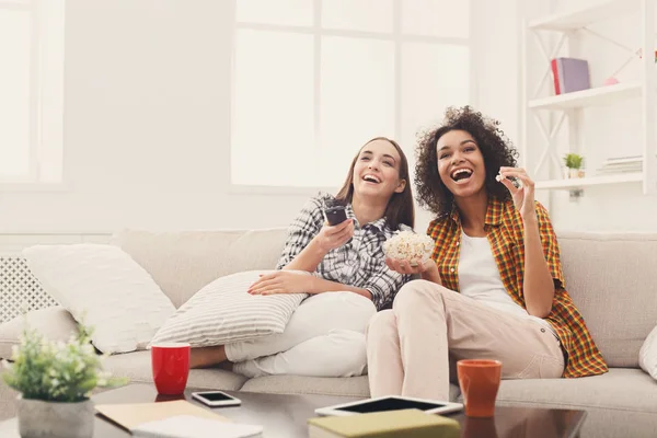 Lächelnde Freundinnen, die zu Hause fernsehen — Stockfoto