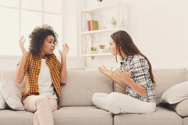 Two female friends sitting on sofa and arguing — Stock Photo, Image