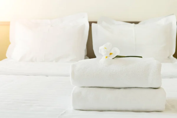 Stapel handdoeken en bloemen op bed in hotelkamer — Stockfoto