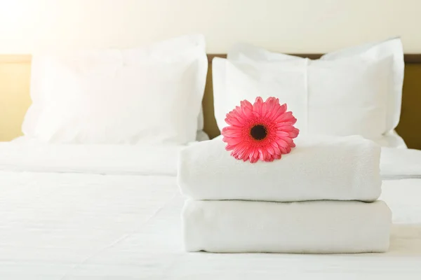 Montón de toallas y flores en la cama en la habitación de hotel —  Fotos de Stock