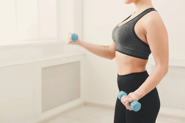 Fitness-Frau mit Kurzhanteln steht am Fenster — Stockfoto