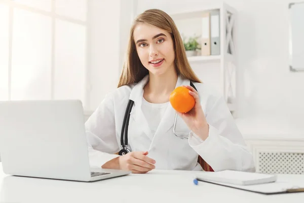 Lachende voedingsdeskundige vrouw met oranje op kantoor — Stockfoto