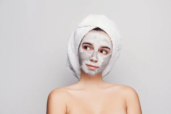 Menina bonita com máscara de argila aplicada no fundo branco — Fotografia de Stock