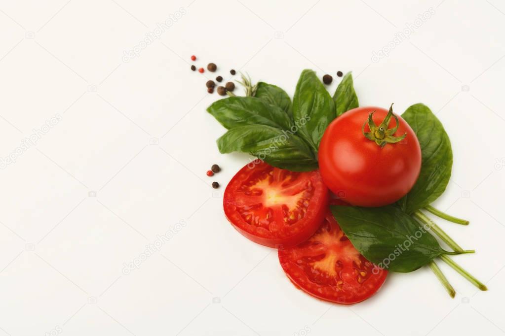Red tomatoes and basil leaves isolated on white