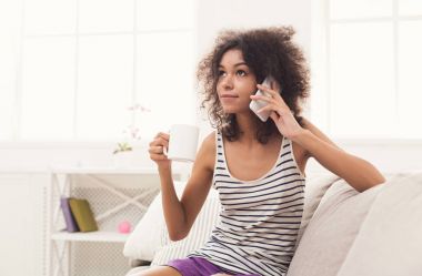 Genç kadın evde cep telefonu üzerinde konuşurken