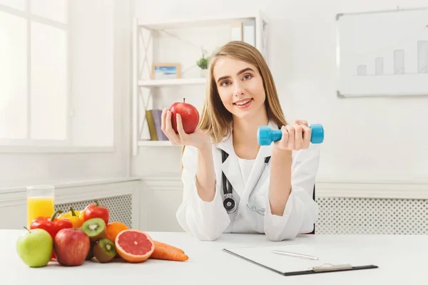 Jeune diététiste avec pomme et haltère à la clinique — Photo