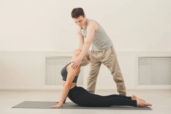 Ung kvinna med yogainstruktör i gymmet — Stockfoto
