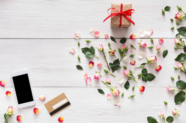 Telefoon scherm met kopie ruimte op wit hout hart roze bloemen, doos van de gift, credite kaart — Stockfoto