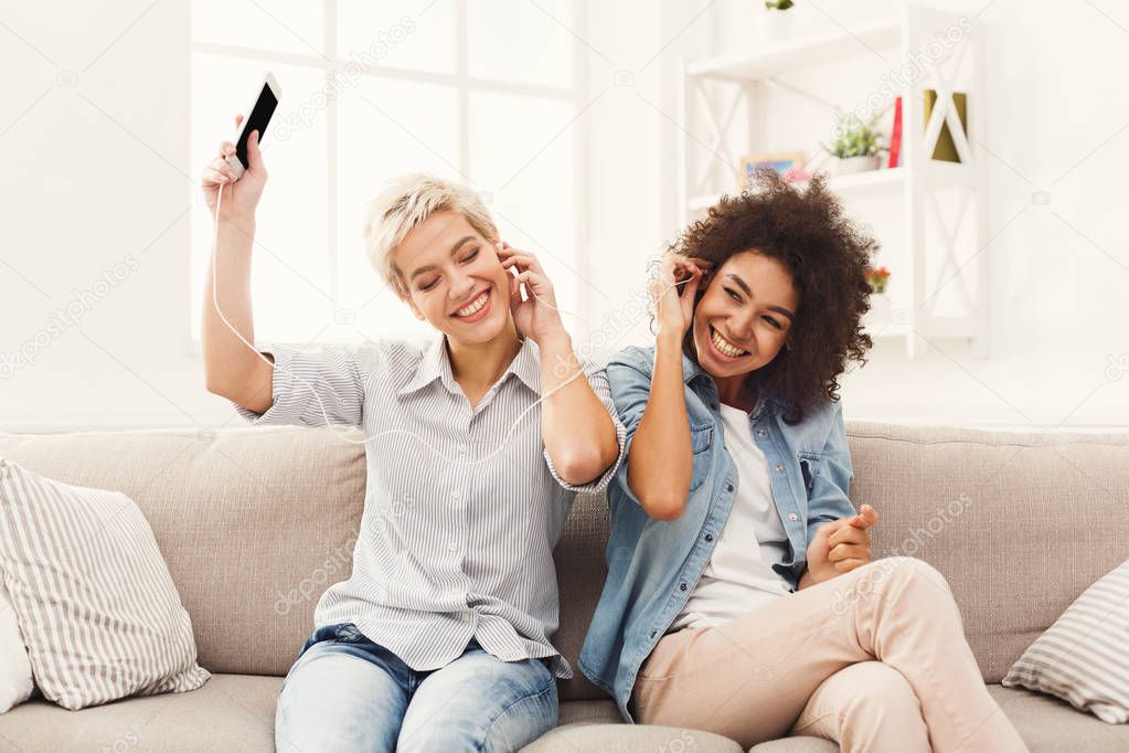 Two women listening music and sharing earphones