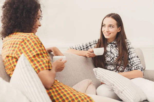 Two young female friends with coffee conversing — Stock Photo, Image