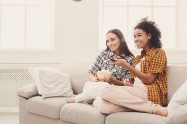 Evde TV izlerken gülümseyen genç kadın