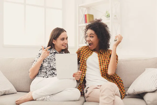 Zwei glückliche aufgeregte Freundinnen mit Tablette. — Stockfoto