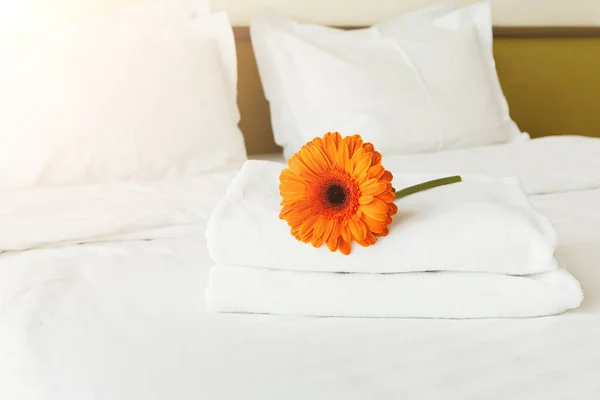 Stapel handdoeken en bloemen op bed in hotelkamer — Stockfoto