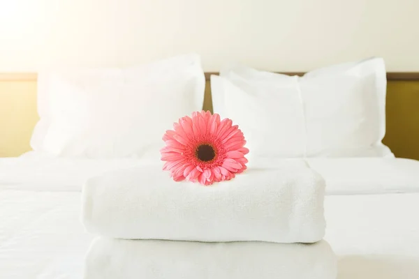 Montón de toallas y flores en la cama en la habitación de hotel — Foto de Stock