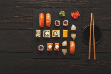 Somon suşi ve rulo siyah ahşap arka plan, üstten görünüm