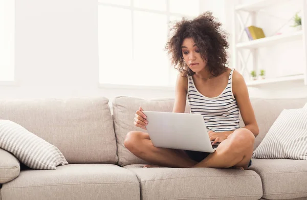 Giovane ragazza con computer portatile seduto sul divano beige — Foto Stock