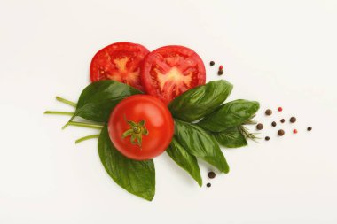 Kırmızı domates ve fesleğen yaprakları üzerinde beyaz izole