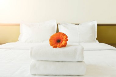 Havlu ve yatak otel odasında çiçek yığını