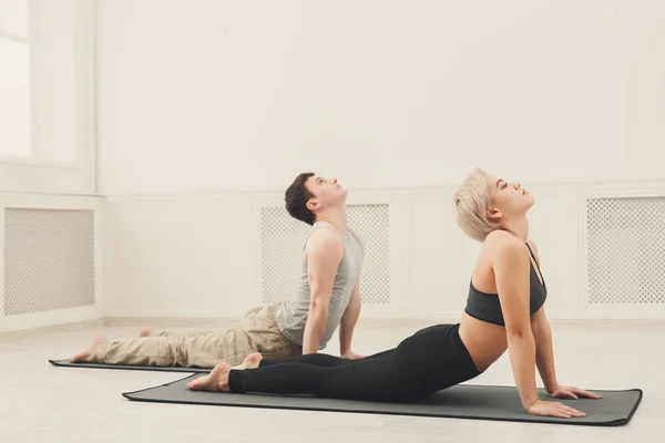 Mannen och kvinnan utbildning yoga i cobra pose. — Stockfoto