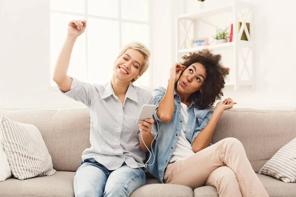 Dos mujeres escuchando música y compartiendo auriculares — Foto de Stock