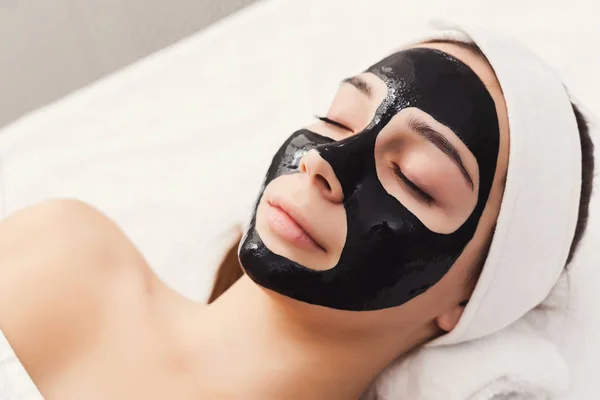 Giovane ragazza con maschera purificante viso nero — Foto Stock