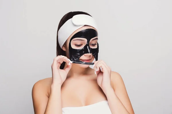 Junges Mädchen mit reinigender schwarzer Gesichtsmaske — Stockfoto